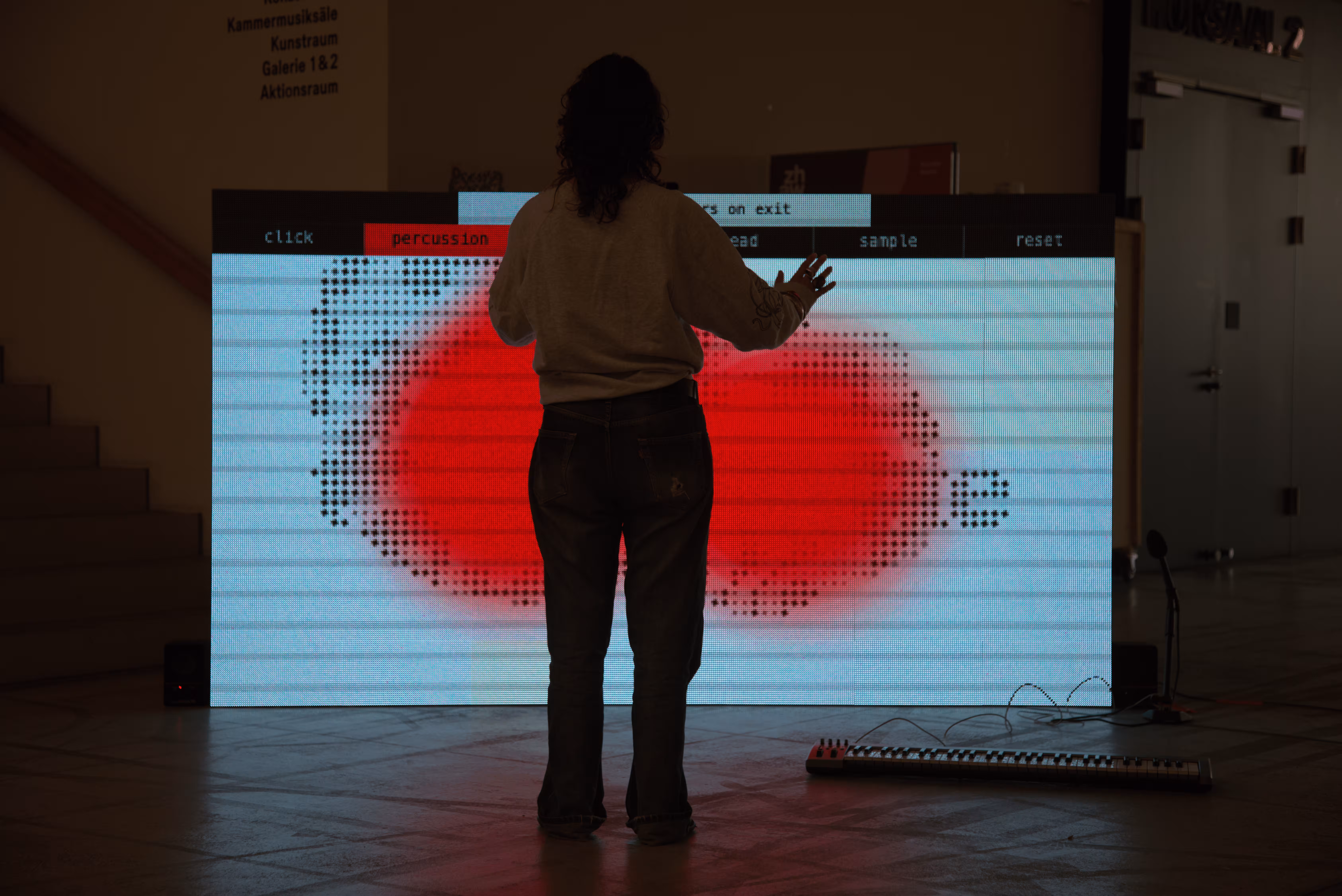 Person in front of the screen installation, red light and a dotted face