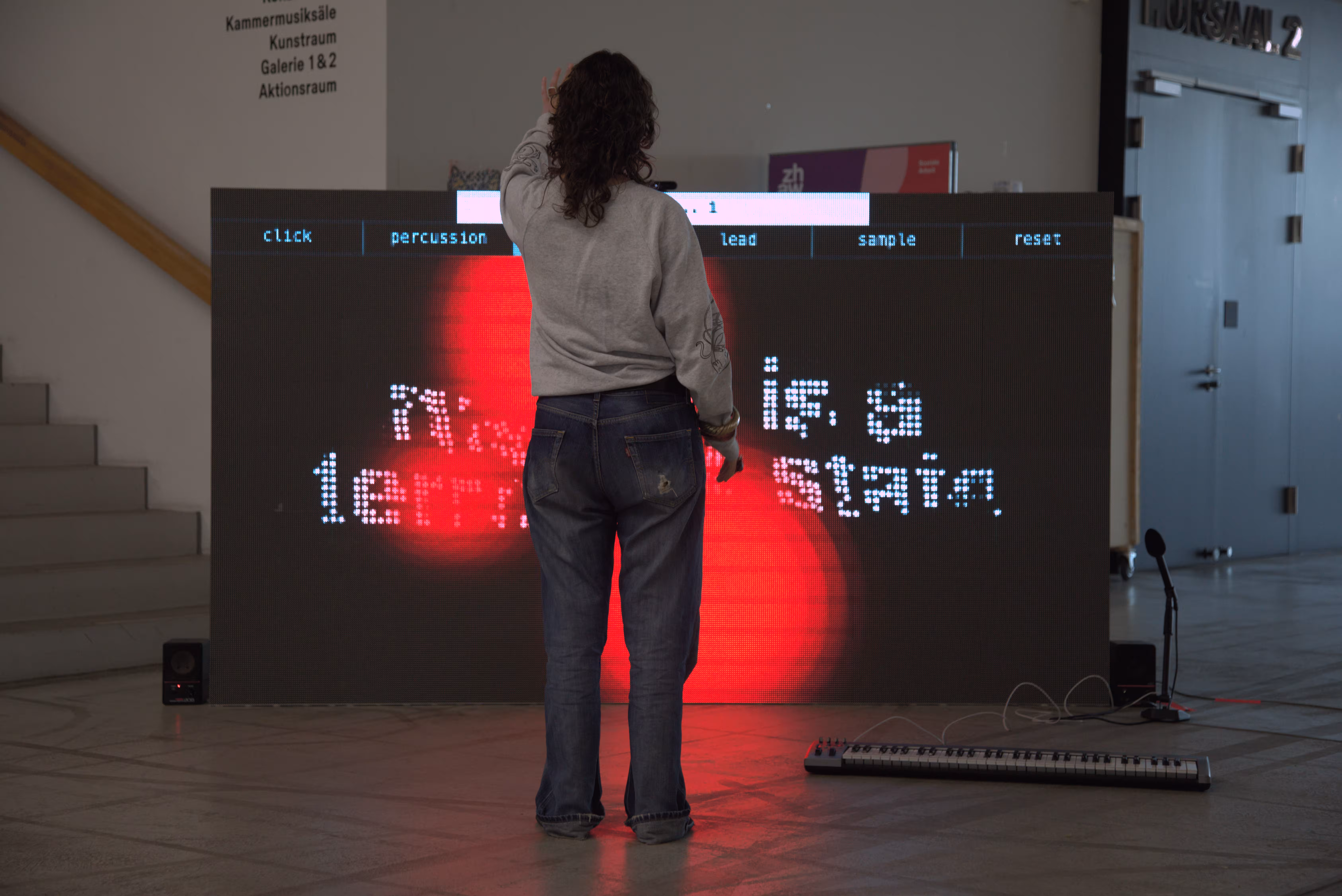 Person in front of the dark screen, pixel text and red light