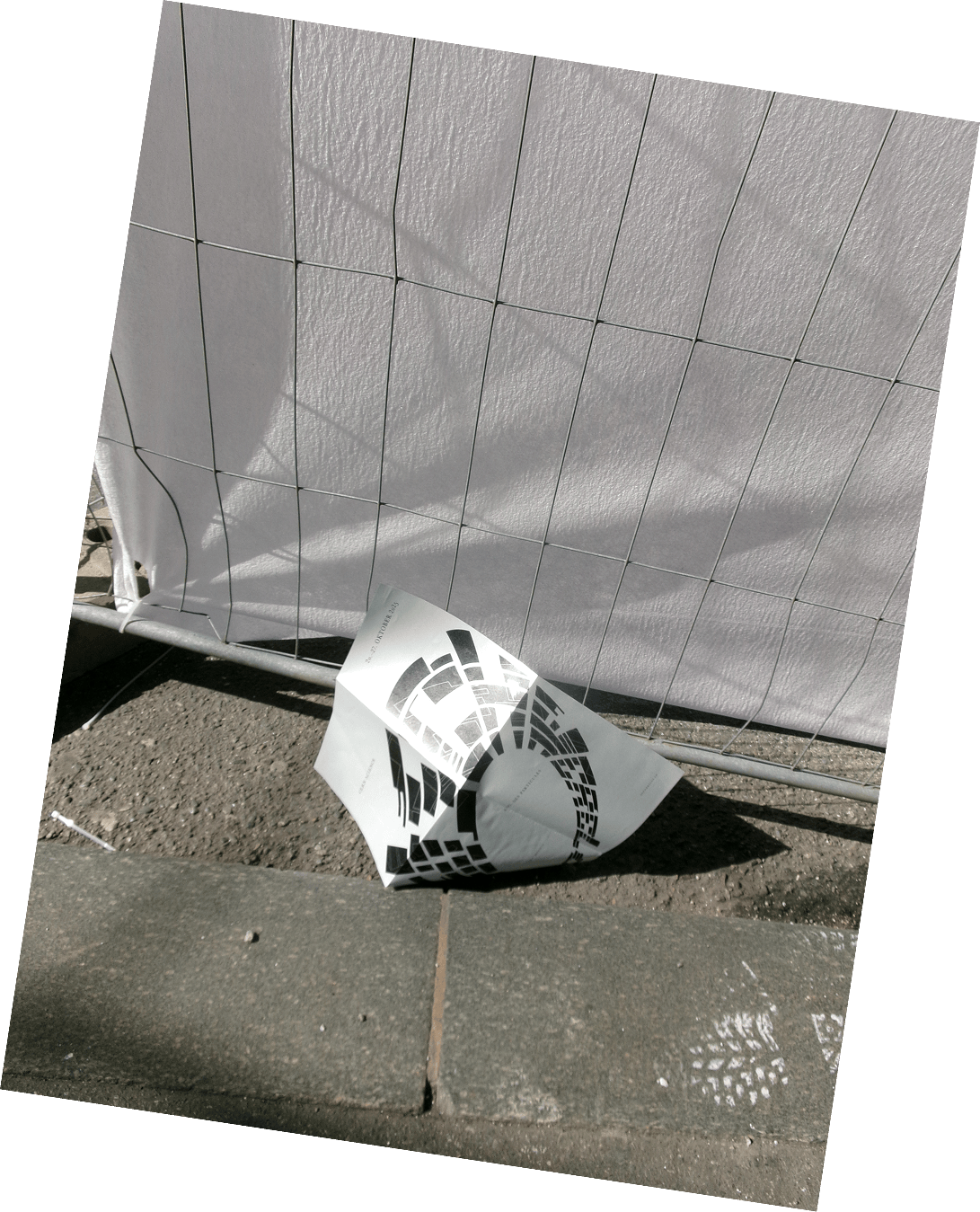 Schwerelos poster folded on the pavement by a construction fence